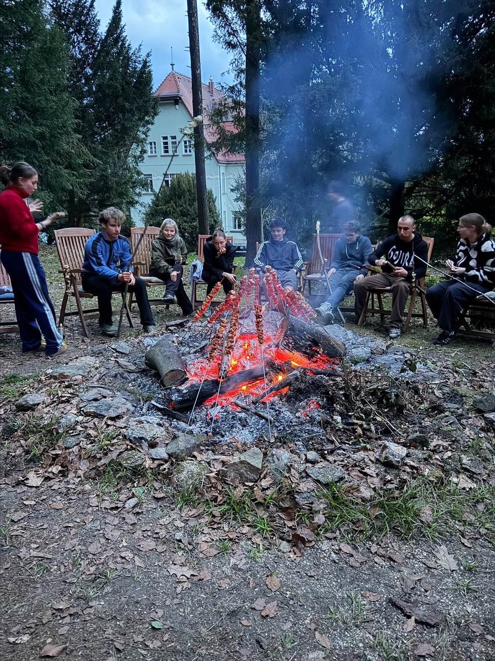 Menschen sitzen im Kreis am Lagerfeuer im Waldpark